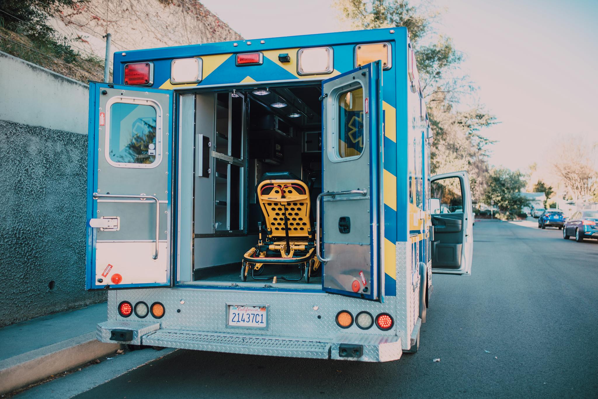 Back view of an open ambulance with a stretcher parked by the roadside.