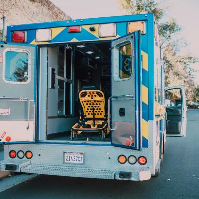 Back view of an open ambulance with a stretcher parked by the roadside.