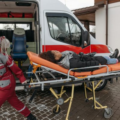 EMTs assist a patient on a stretcher into an ambulance, highlighting emergency response.