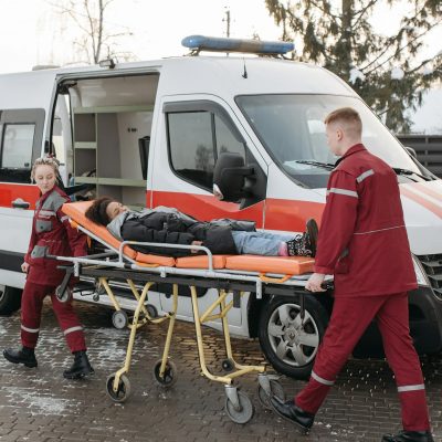 Paramedics transferring a patient on a stretcher to an ambulance for emergency care.